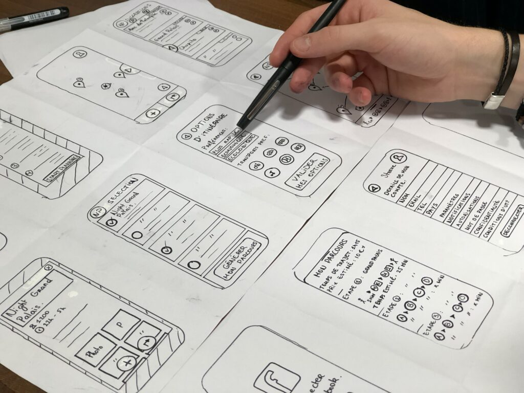 Personne tenant un stylo et travaillant sur des maquettes papier